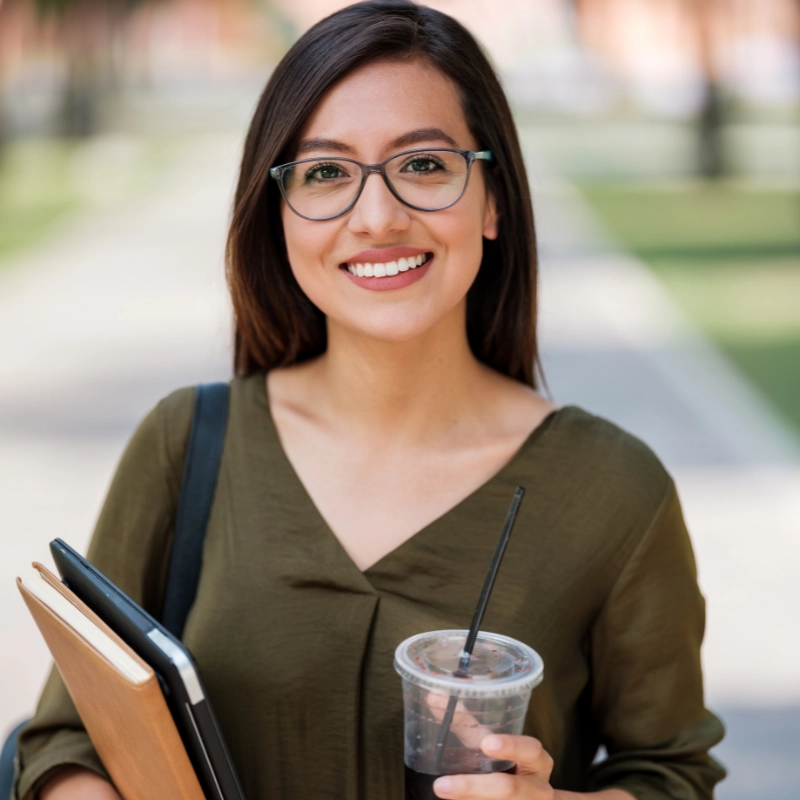 Una mujer joven sonriendoy cargando un cuaderno